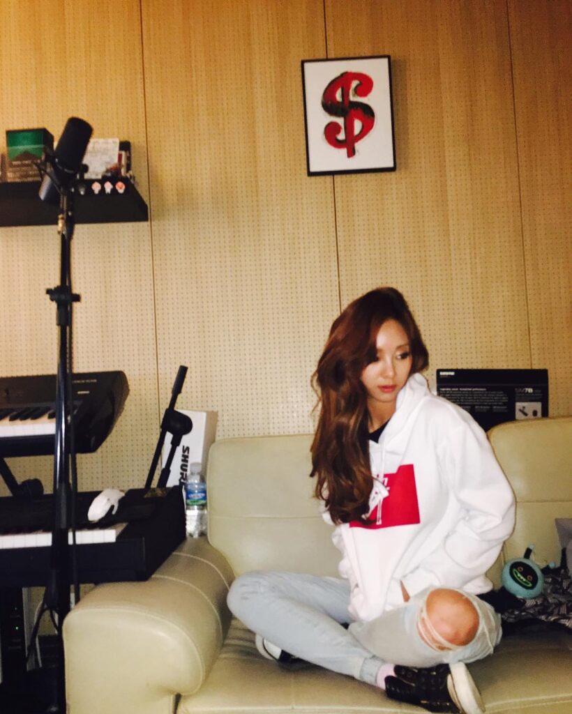 G.NA is sitting on the couch in the music studio