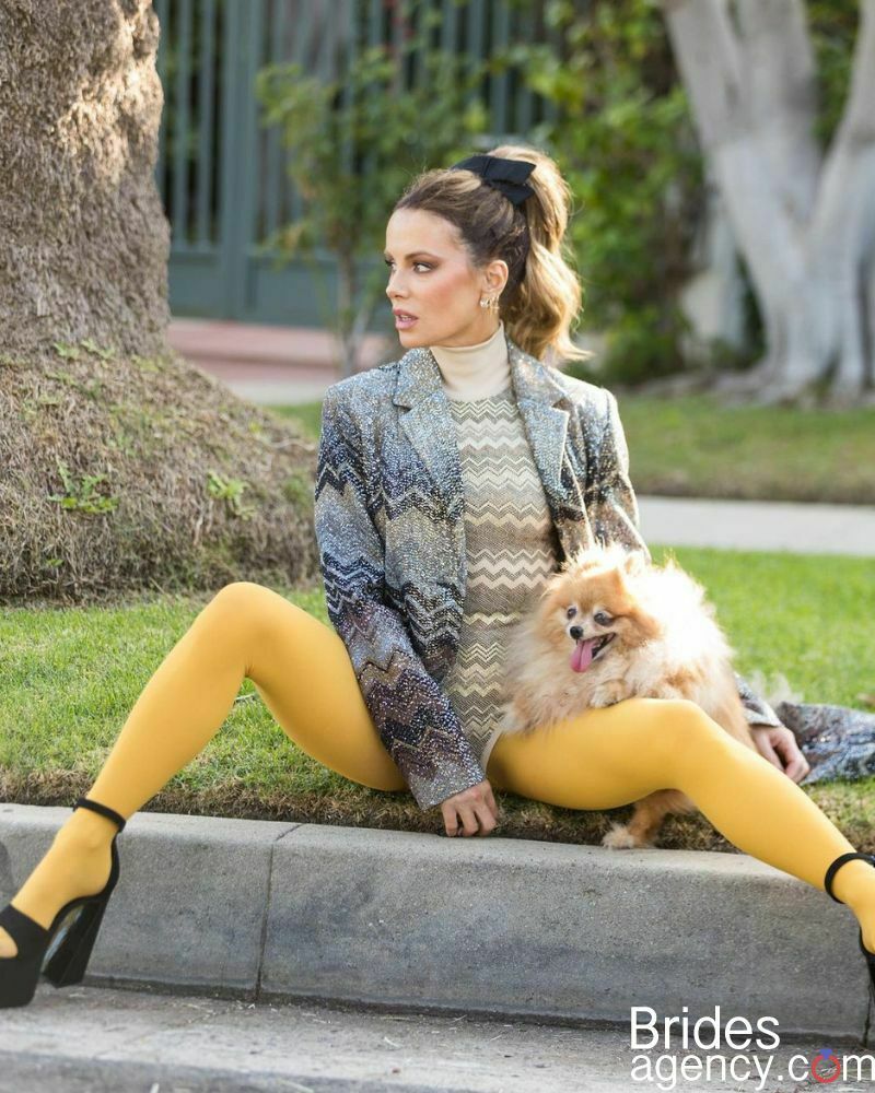 Kate Beckinsale in extravagant clothes sits on the street
